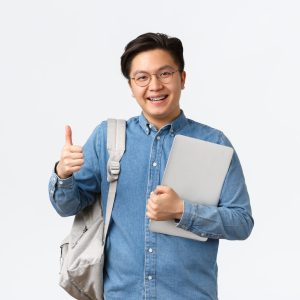 University, study abroad and lifestyle concept. Satisfied happy asian male student in glasses and shirt showing thumbs-up in approval, likes studying in college, holding laptop and backpack.
